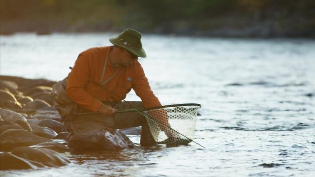 Portrait of fisherman with catch in keep net freshwater river Canada