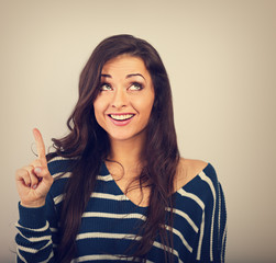 Beautiful positive young casual woman in warm sweater have an idea and holding finger up on empty copy space background. Toned closeup portrait