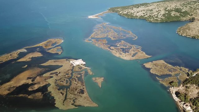 Boat sailing through .Most unique Albanian castle surrounded by water in lagoon.  Location is Butrint, Saranda, Vlora, Albania (Albanian Riviera)