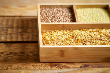 different, colorful types of groats in a wooden square box