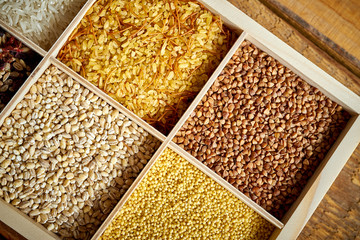 different, colorful types of groats in a wooden square box