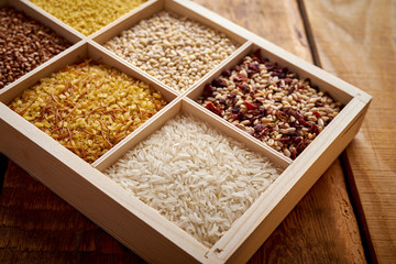 different, colorful types of groats in a wooden square box