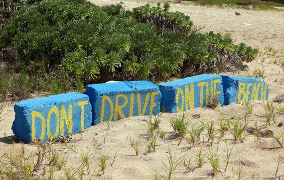 The English words Don't drive on the beach painted on bricks