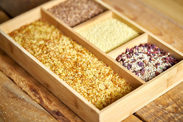 different, colorful types of groats in a wooden square box