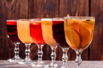 Assorted mulled wine. Variety of mulled wine in beautiful glasses standing in a row on a dark wooden background. advertising photo of mulled wine. Close up