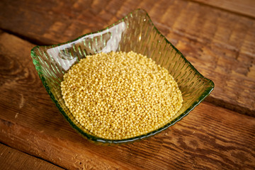 millet in a green glass bowl on an old wooden table