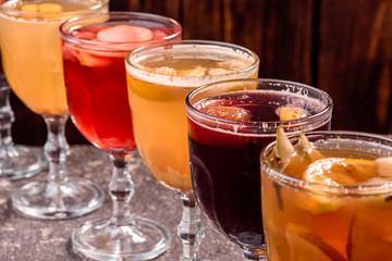 Assorted mulled wine. Variety of mulled wine in beautiful glasses standing in a row on a dark wooden background. advertising photo of mulled wine. Close up