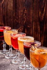 Assorted mulled wine. Variety of mulled wine in beautiful glasses standing in a row on a dark wooden background. advertising photo of mulled wine. Close up