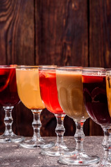 Assorted mulled wine. Variety of mulled wine in beautiful glasses standing in a row on a dark wooden background. advertising photo of mulled wine. Close up
