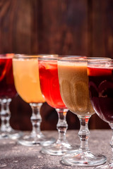 Assorted mulled wine. Variety of mulled wine in beautiful glasses standing in a row on a dark wooden background. advertising photo of mulled wine. Close up