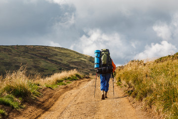 A traveler with trekking poles and backpack in the mountains. Outdoor activity concept