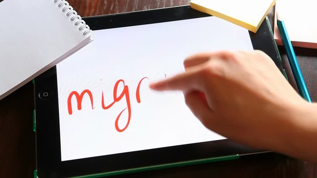 Migration - hand write word on tablet, migrants concept