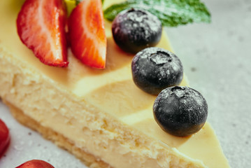 Berry cheesecake and cappuccino. Cheesecake with strawberries, blueberries and mint on a white plate on a copper background. Close up
