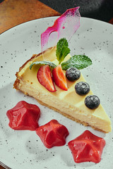 Berry cheesecake and cappuccino. Cheesecake with strawberries, blueberries and mint on a white plate on a copper background. Close up