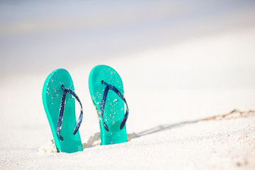 Summer mint flip flops with sunglasses on white beach