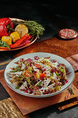 Salad with pomegranate, corn, tomatoes, arugula, parmesan cheese and cranberries on a white plate on a copper background. Fresh vegetables in the background. top view. flat lay. Close-up