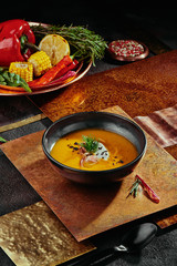 Cream soup of sweet potato with truffle, cheese and bacon in a black plate on a copper background. close up.