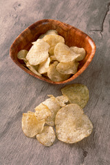 Potato chips on a bowl over wood background