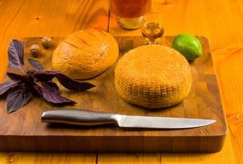 national Adyghe cheese homemade on a cutting Board with a knife, Basil, parsley, lime, sesame oil,...