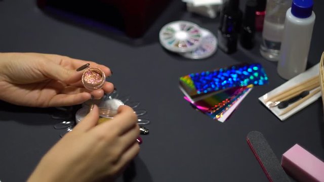 Woman showing nail art product. Girl opens boks with mirror powder glitter