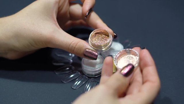 Woman showing nail art product. Girl opens boks with mirror powder glitter