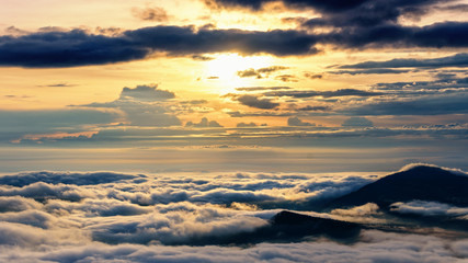 Fototapeta na wymiar Beautiful nature landscape the sun is above the sea fog that covers the mountains and bright sky during sunrise in the winter at viewpoint of Phu Ruea National Park, Loei province, Thailand.