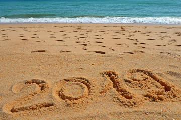 2019 YEAR inscription written in the wet yellow beach sand. Concept of celebrating the New Year, party on the shores of the Atlantic Ocean.