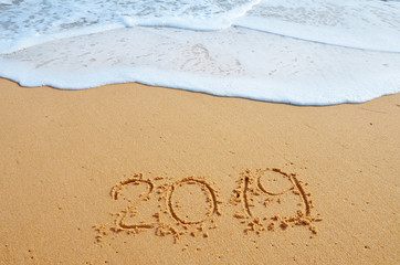 2019 YEAR inscription written in the wet yellow beach sand. Concept of celebrating the New Year, party on the shores of the Atlantic Ocean..