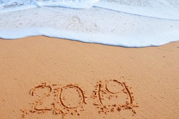 2019 YEAR inscription written in the wet yellow beach sand. Concept of celebrating the New Year, party on the shores of the Atlantic Ocean..