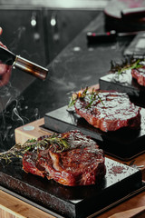 Fermented steak. Ribeye steaks on a square black stone plates. close up. dark background
