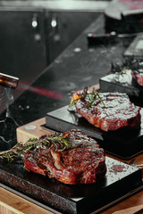 Fermented steak. Ribeye steaks on a square black stone plates. close up. dark background
