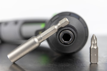 Bits for a screwdriver on a metal workshop table. Workshop accessories for mechanics. Light background.