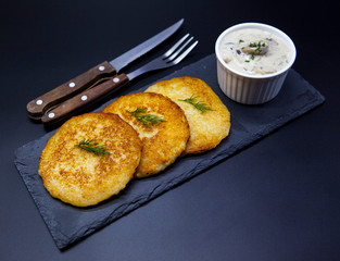 Traditional tasty hash brown with cream sauce on a stone black plate