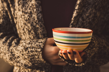 Woman holding a ceramic cup with stripes in left hand