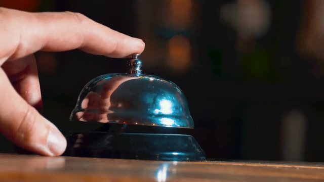 Hotel ring on wooden table background. Bell call vintage service with hand. Restaurant bell vintage on bokeh. Vintage hotel reception service desk bell lifestyle.