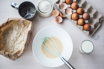 Process of making the dough, woman's hand whips eggs and flour in bowl Flat lay composition of ingredients and batter.selective focus