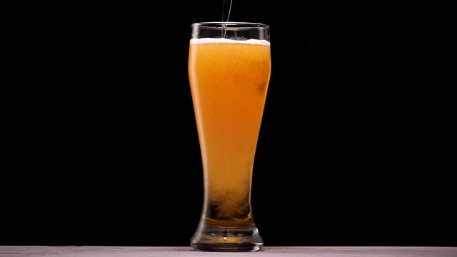 Light beer pouring in glass. With bubbles and foam.