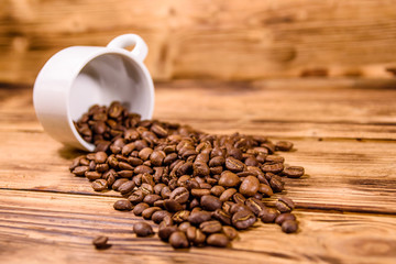 White cup and scattered coffee beans on wooden table