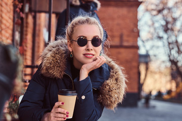 A beautiful young woman drinking coffee in the outdoor cafe.