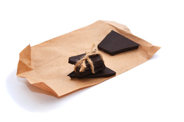 Three pieces of bitter, dark chocolate bar bound by twine, isolated on white background, close-up view. Homemade chocolate.