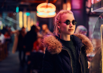 Fototapeta premium A sensual girl standing in the night on the street. Illuminated signboards, neon, lights.