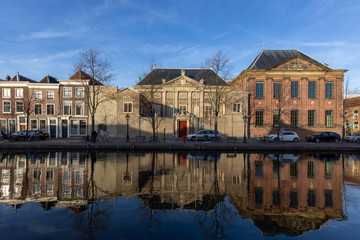 Obraz premium Autumn picturesque view on an old part of the city Leiden with classic facades against a blue sky with the scene doubled as a reflection in the water of the passing canal