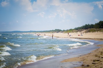 Summer on polish beach, tourists silhouettes on sea shore