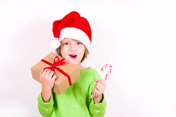 Happy boy in Santa red hat holding Christmas gift in hand. Christmas concept.