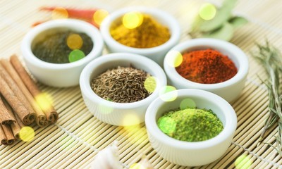 Various colorful spices in bowls on wooden table