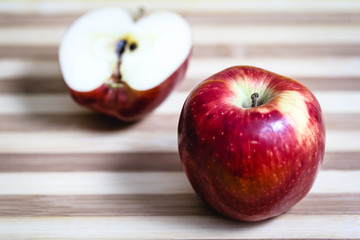 Red apple next to slices of another apple.
