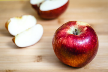 Red apple next to slices of another apple.