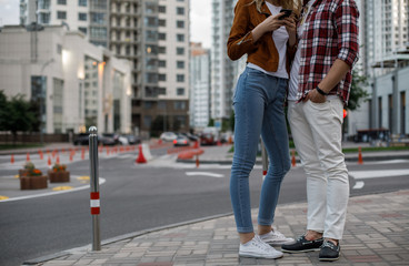 Couple is embracing in city. They wearing casual clothes style. She using handy. Copy space on left side