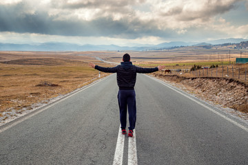 Man is standing in the middle of the long road