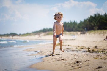 Young caucasian boy playing on sea shore at sunny summer